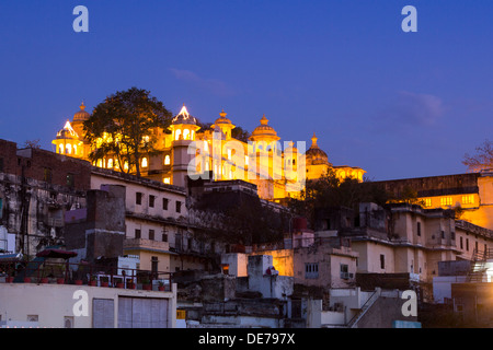 India Rajasthan, Udaipur, vista sopra i tetti verso il palazzo di città illuminata al crepuscolo Foto Stock