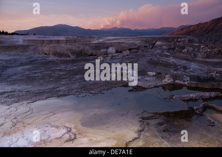 Fotografia del tramonto su Mammoth Hot Springs con un pennacchio di fumo di un incendio in background. Foto Stock
