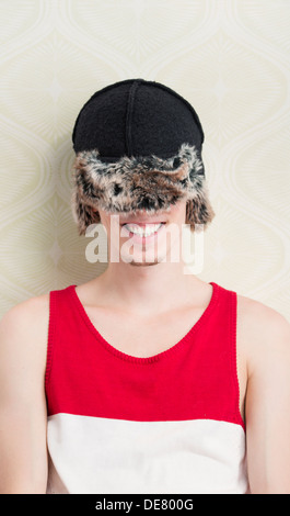 Stile di vita ritratto di ridere giovane con cappello invernale viene tirato verso il basso per coprire i suoi occhi Foto Stock