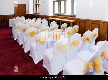 Cerimonia di nozze mobili e sedie con i coperchi di colore bianco e nastro giallo Foto Stock