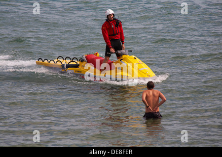 RNLI Lifeguard su jetski in pattuglia dando consigli all'uomo in mare a Bournemouth Beach durante Bournemouth Air Festival, Dorset UK nel mese di agosto Foto Stock