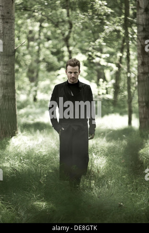 Uomo con mantello nero nella foresta Foto stock - Alamy