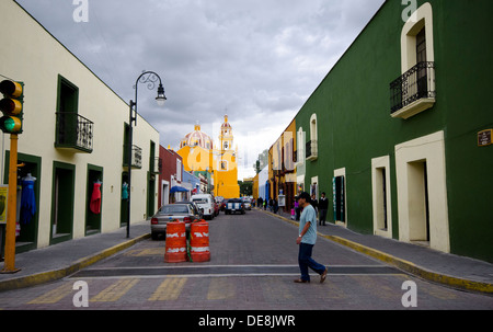 L'uomo attraversando a piedi attraversando in Cholula in Messico con colore giallo brillante chiesa in background Foto Stock