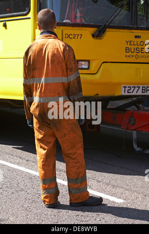 Gli autobus gialli ingegnere bus watching essendo preparato per il traino di distanza dal veicolo di recupero in Bournemouth Foto Stock