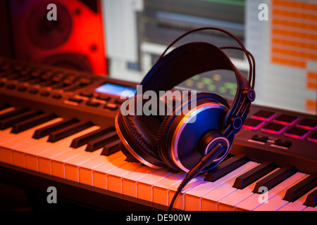 Le cuffie si appoggiano su una tastiera MIDI in un home studio. Foto Stock