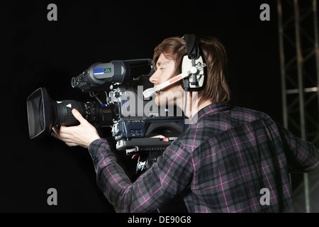 Giovane uomo operando una telecamera in uno studio TV. Foto Stock