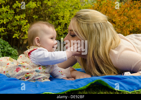 La madre gioca con otto mesi di età figlia al di fuori in giardino Foto Stock