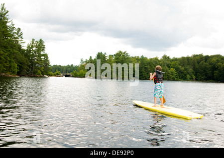 Ragazzo giovane stand up paddle boarding Foto Stock