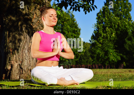 Giovane donna durante la meditazione yoga nel parco Foto Stock