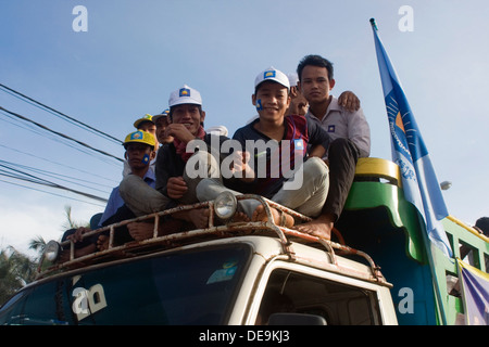 Le persone sono a cavallo sulla parte superiore di un carrello durante una campagna di rally per la contrapposta CNRP guidato da Sam Rainsy in Kampong Cham, Cambogia Foto Stock