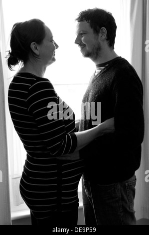 In bianco e nero girato di una donna incinta e il suo partner guardando teneramente a ciascun altro Foto Stock