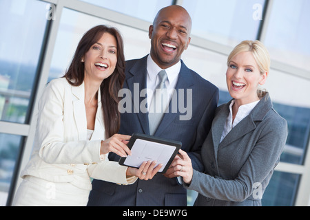 Uomo e due donne, imprenditore e imprenditrici interracial team tramite computer tavoletta al di fuori in città moderna Foto Stock