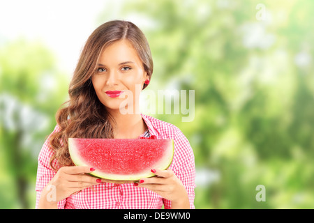 Sorridente bella donna tenendo una fetta di cocomero Foto Stock