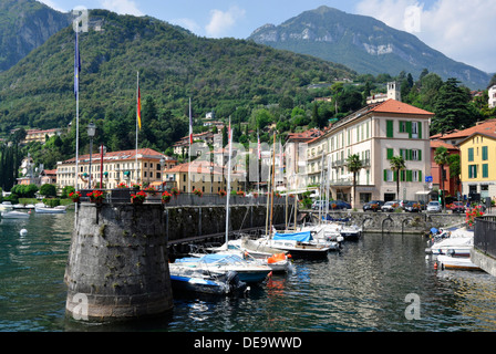 Italia - Lago di Como - Menaggio - il porto - ormeggiate barche - fiori - sfondo città + montagne - luce solare + blu cielo Foto Stock