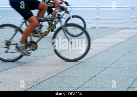 Persone a cavallo bike lungo la promenade. La spiaggia di San Lorenzo, Gijon, Asturias, Spagna. Foto Stock