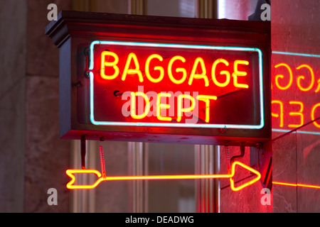 Un neon rosso segno indica la strada per il deposito dei bagagli nella stazione ferroviaria Foto Stock