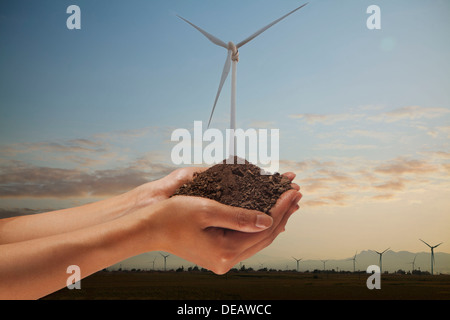 Mani tenendo il terreno con una turbina eolica crescente dal centro Foto Stock