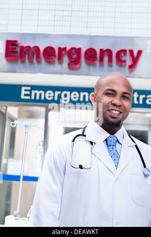 Ritratto di sorridere medico al di fuori dell'ospedale, sala di emergenza sign in background Foto Stock