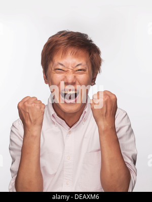 Uomo eccitato con i pugni sollevato e la bocca aperta, studio shot Foto Stock