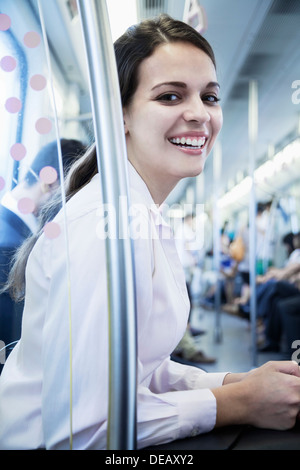 Ritratto di giovane imprenditrice seduta sulla metropolitana e guardando la telecamera Foto Stock