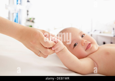 Madre mentre tiene il suo bambino in mano i medici office Foto Stock