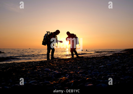 Due uomini in silhouette, scuba diving al tramonto, Cardigan Bay, Aberystwyth Wales UK Foto Stock