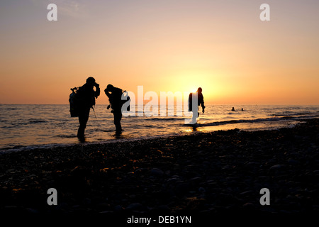 Tre Uomini in silhouette, scuba diving al tramonto, Cardigan Bay, Aberystwyth Wales UK Foto Stock