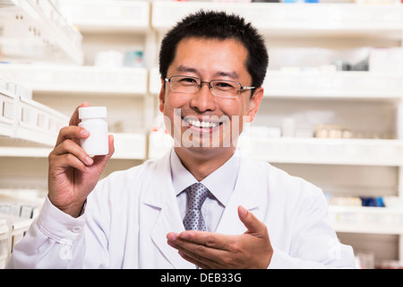 Ritratto di sorridere il farmacista in possesso di una prescrizione farmaci in bottiglia la sua mano Foto Stock