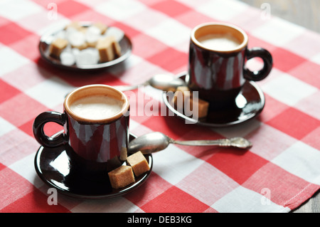 Due tazze di caffè in tazze marrone sul tovagliolo a scacchi Foto Stock