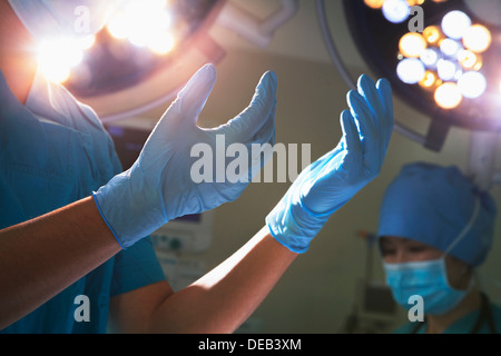 Sezione mediana vista delle mani in guanti chirurgici e luci chirurgica in sala operatoria Foto Stock