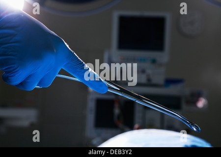 Close-up di mano guantata holding forbici chirurgiche, in sala operatoria, ospedale Foto Stock