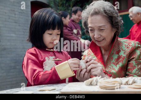 Nonna e nipote rendendo gnocchi in Abbigliamento tradizionale Foto Stock