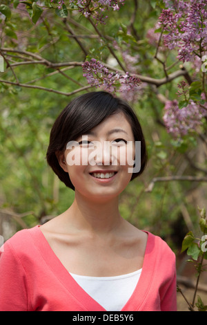 Ritratto di sorridente giovane donna con media lunghezza capelli all'aperto nel parco di primavera Foto Stock