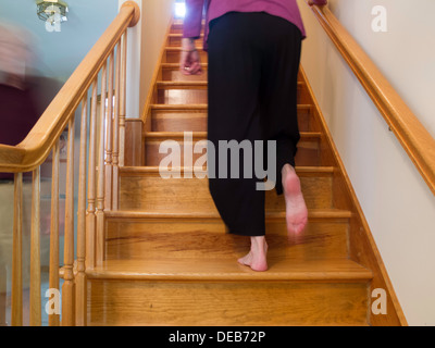 Una donna a piedi nudi sta camminando su un volo residenziale delle scale, Stati Uniti Foto Stock