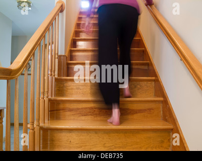 Una donna a piedi nudi sta camminando su un volo residenziale delle scale, Stati Uniti Foto Stock