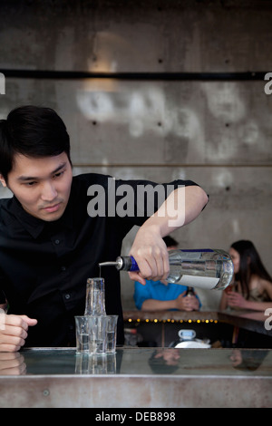 Barista liquore di colata su shot piramide in vetro Foto Stock