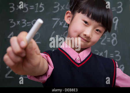 Ritratto di schoolgirl davanti di blackboard azienda chalk Foto Stock