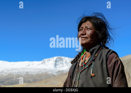 Anziana donna nomade, montagne coperte di neve in lontananza, Korzok, Ladakh, Jammu e Kashmir India Foto Stock