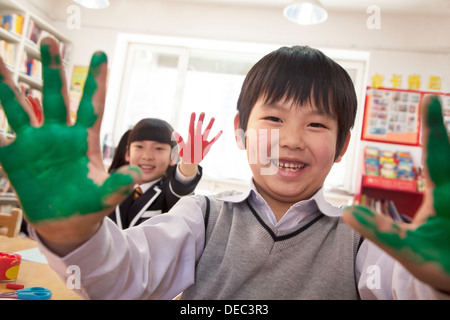 La scuola dei bambini che mostrano le loro mani coperte di vernice Foto Stock