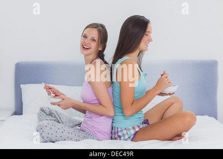 Amici nel letto mangiare cereali Foto Stock