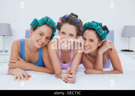 Ragazze in i capelli rulli giacente a letto Foto Stock