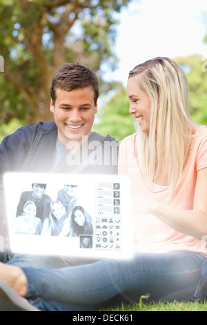 Sorridente coppia giovane guardare le foto sull'interfaccia digitale Foto Stock