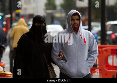 Oxford Street, Londra, Regno Unito. Xvi Sep, 2013. Una donna che indossa un full face veil cammina al fianco di un partner di sesso maschile in Oxford street come un liberale britannica politico democratico Jeremy Browne provoca polemiche dopo la chiamata per un dibattito nazionale sulla questione se le donne dovrebbero indossare il velo islamico o 'Niqba' in luoghi pubblici. Credito: amer ghazzal/Alamy Live News Foto Stock