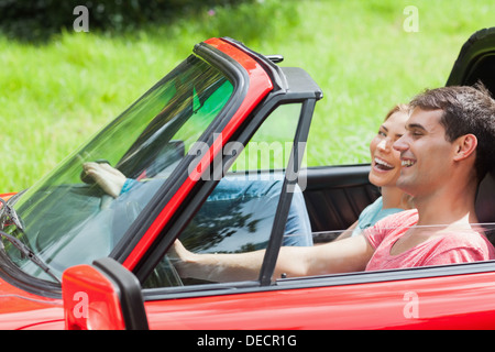 Sorridente coppia giovane avente una corsa in rosso cabriolet Foto Stock