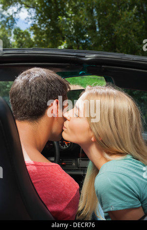 Attraente bionda baciare il suo fidanzato pur avendo un giro in cabriolet Foto Stock