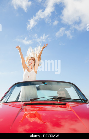 Donna felice in piedi in cabriolet mentre il suo fidanzato la guida Foto Stock