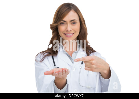 Medico sorridente puntando verso qualcosa in mano Foto Stock