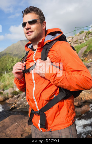 L'uomo indossando giacca impermeabile e occhiali da sole sorridente Foto Stock