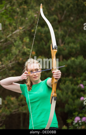 Concentrando donna bionda praticare il tiro con l'arco Foto Stock