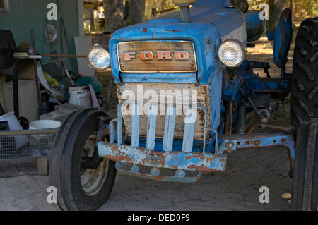 Il vecchio trattore Ford siede sotto un fienile. Foto Stock